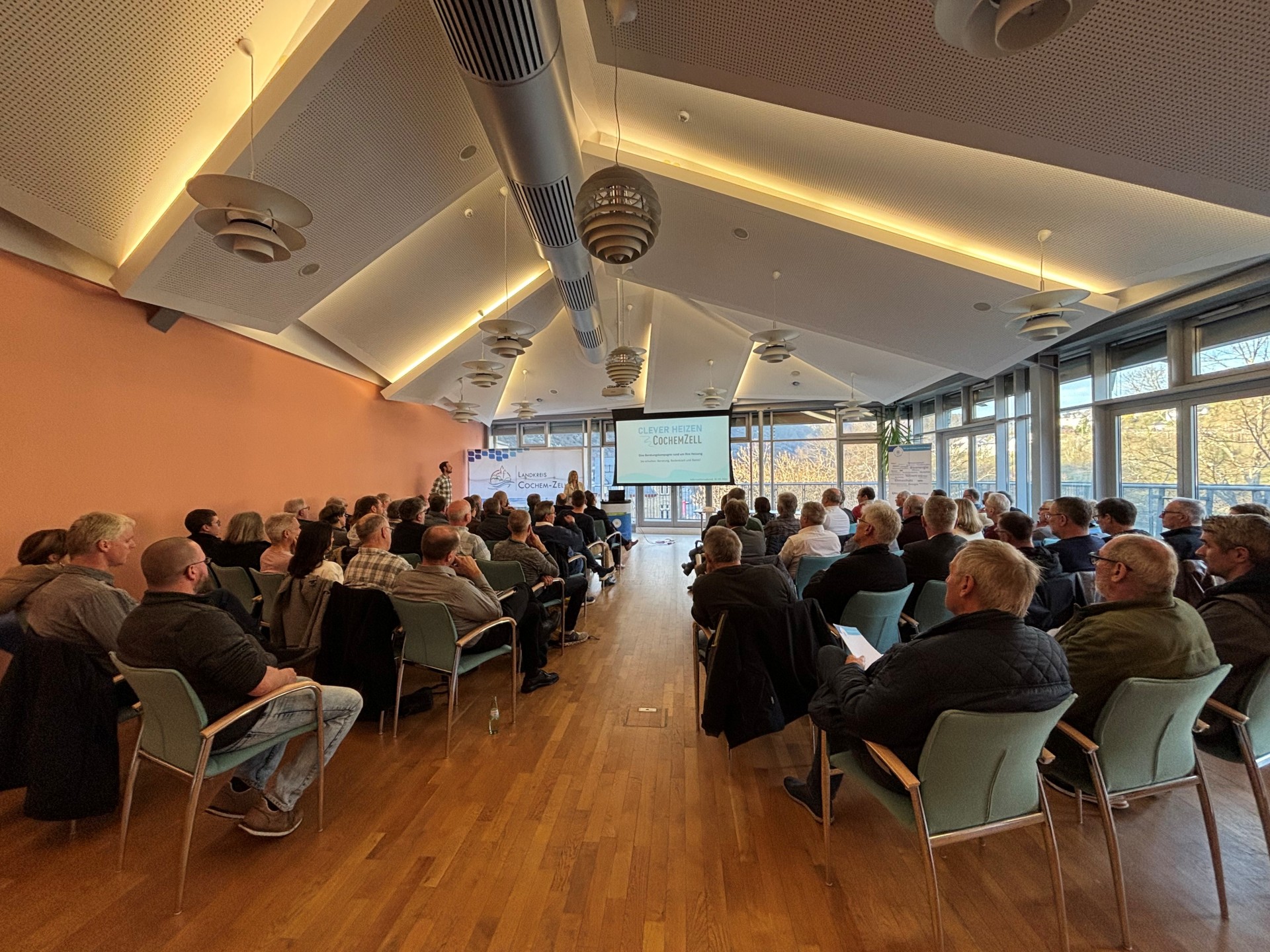 Viele Besucherinnen und Besucher sitzen in einem großen Saal und hören der Landrätin zu.