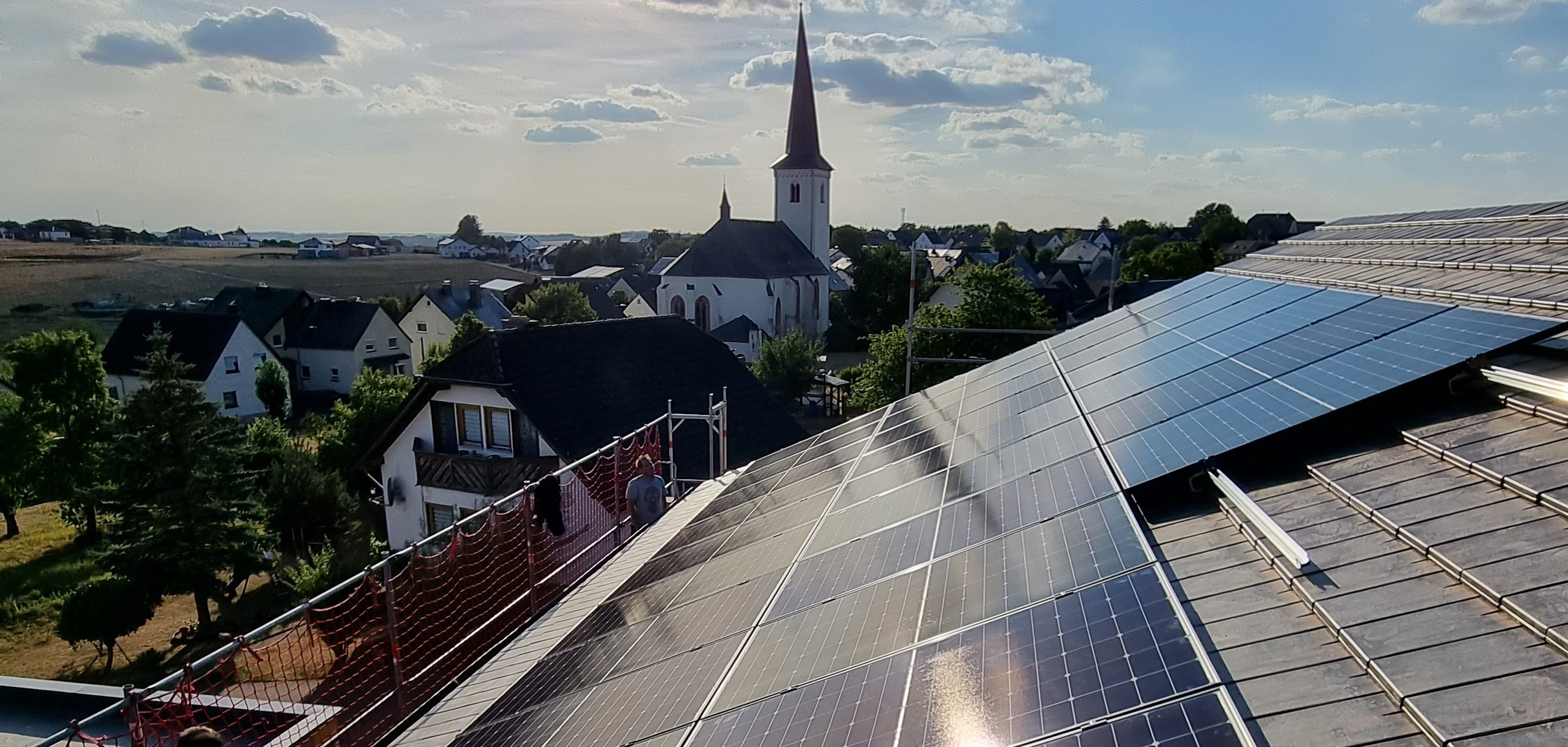 Foto von PV-Aufdachanlage mit Kirchturm im Hintergrund 