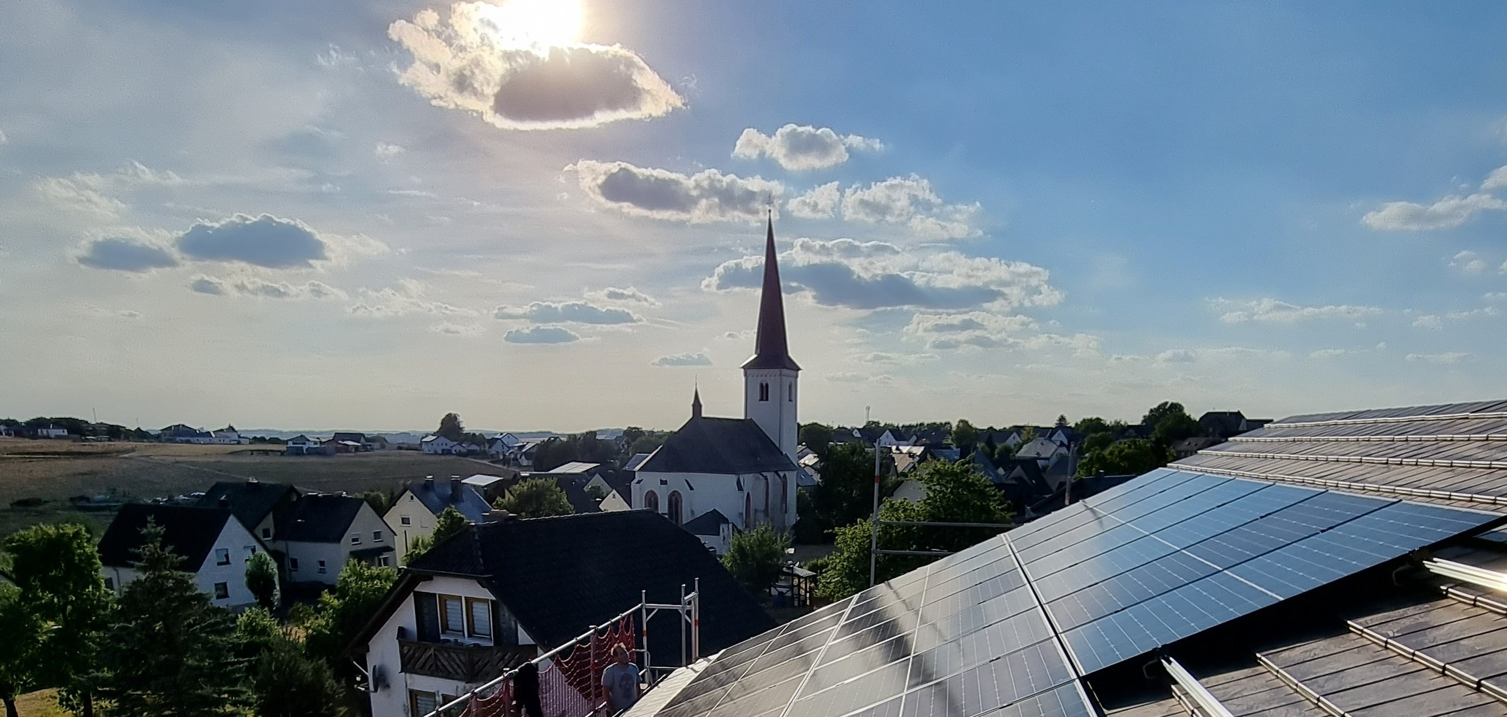 Foto von PV-Aufdachanlage mit Kirchturm im Hintergrund 
