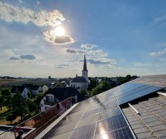 Foto von PV-Aufdachanlage mit Kirchturm im Hintergrund 