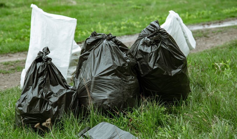 Schwarze und weiße Mülltüten auf Wiese