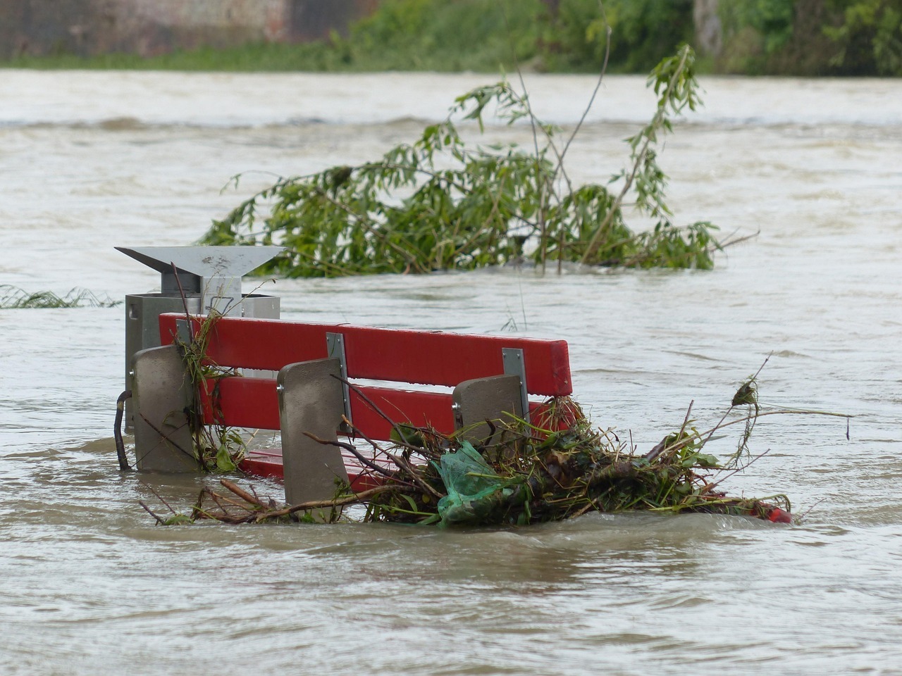 Hochwasserlage überflutet Bank. Treibgut bleibt an Bank hängen.