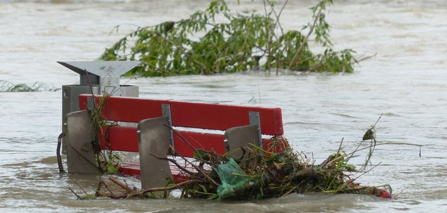 Hochwasserlage überflutet Bank. Treibgut bleibt an Bank hängen.