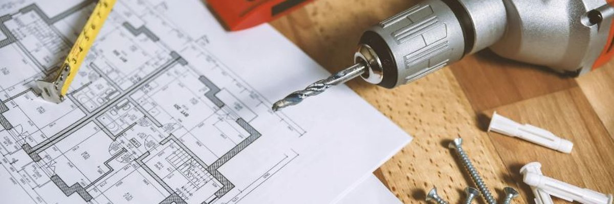 Tisch mit Bauplänen, Maßband, Akkuschrauber, Schrauben, Dübeln und Wasserwaage