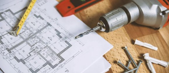 Tisch mit Bauplänen, Maßband, Akkuschrauber, Schrauben, Dübeln und Wasserwaage