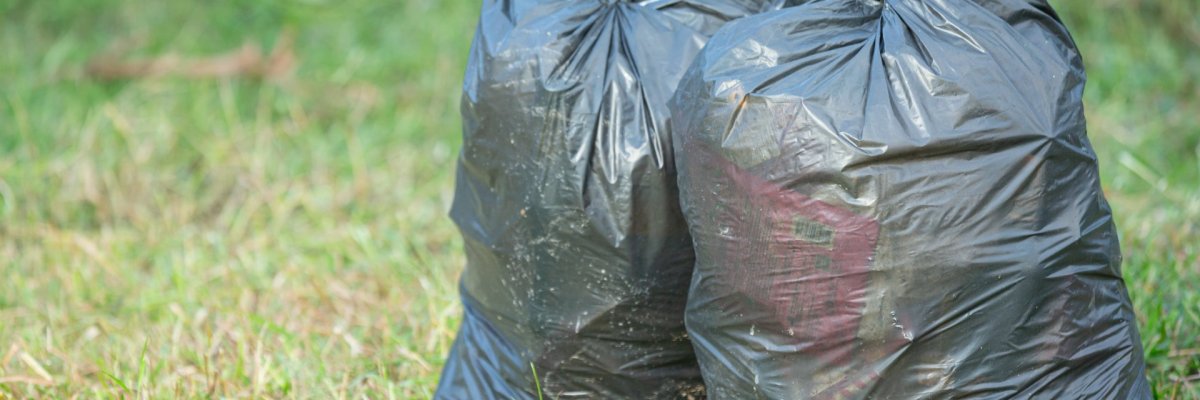 Zwei schwarze Müllsäcke auf Wiese